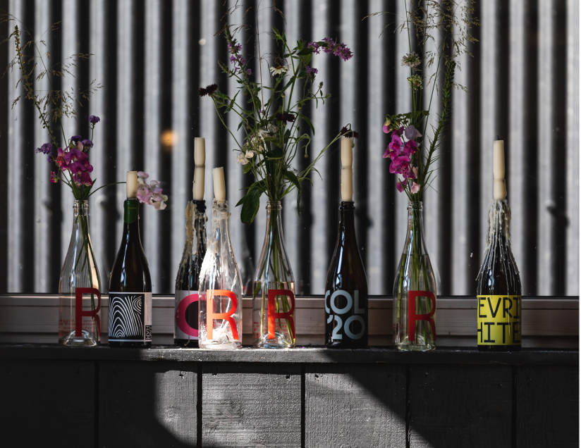 Empty wine bottles holding flowers and candles on a table at Tillingham