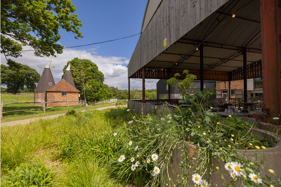 View of the open-air dining area at Tillingham, with a traditional oast house in the background