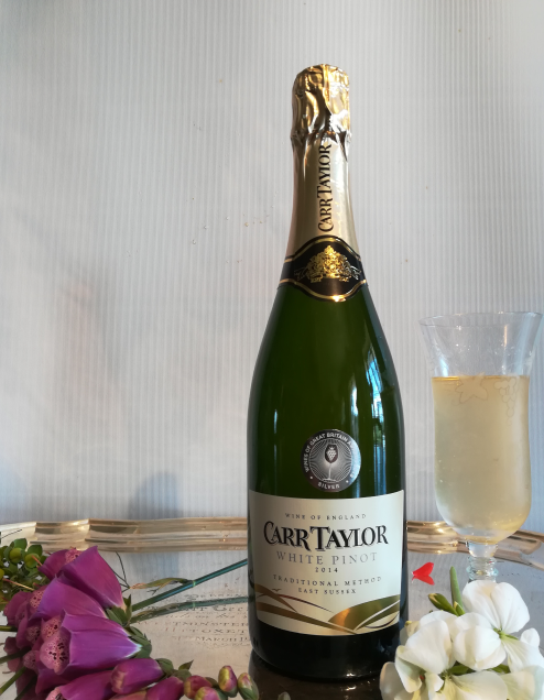 A bottle of Carr Taylor white pinot on a table with flowers