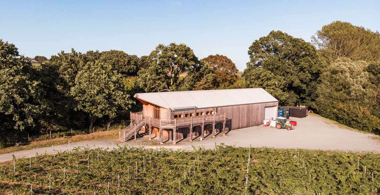 Aerial view of the wooden winery building at Oastbrook Vineyard, surrounded by trees and vineyard rows