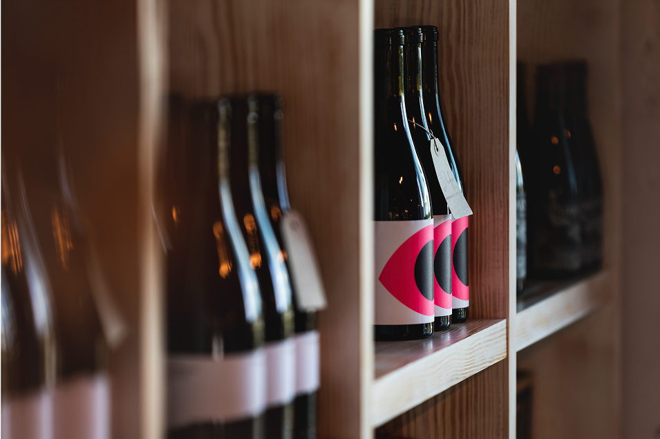 Close-up of wine bottles on wooden shelves in the tasting room at Tillingham