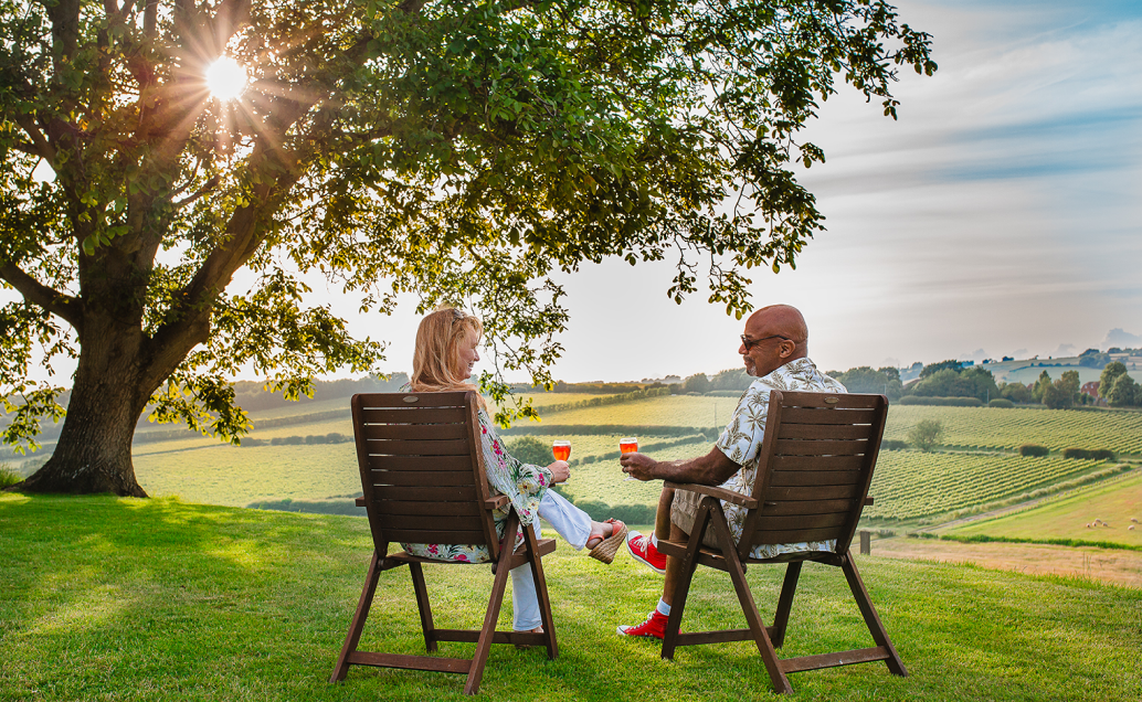 Two people sitting enjoying a glass of wine overlooking Charles Palmer Vineyards