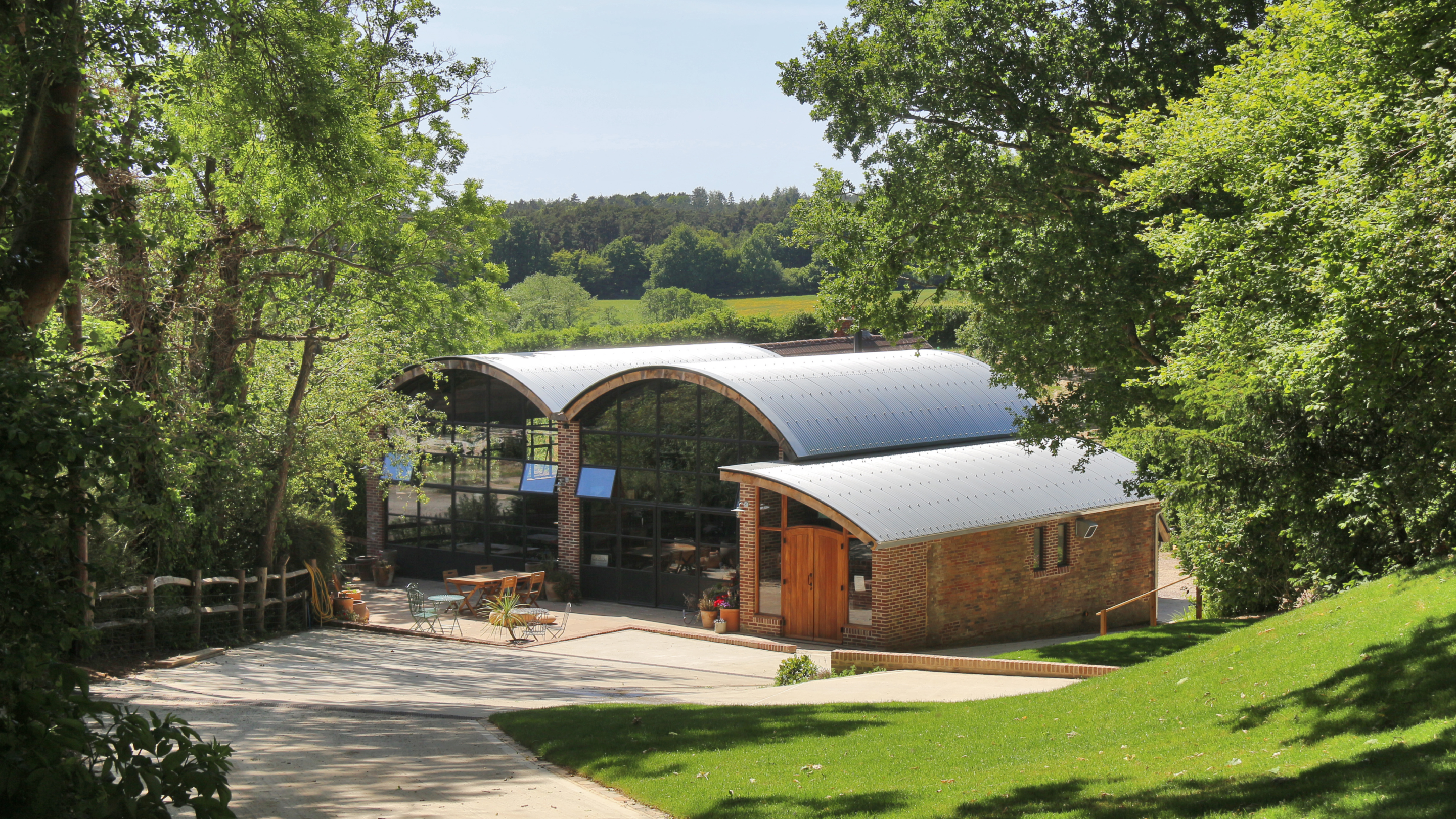 A view of Sedlescombe Organic Vineyard and outdoor seating framed by trees